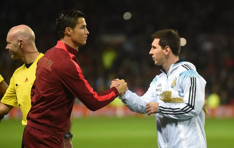 Argentina striker Lionel Messi (R) shakes hands with Portugal's striker Cristiano Ronaldo (L) ahead of kick off of the international friendly football match between the Argentina and Portugal at Old Trafford in Manchester on November 18, 2014. AFP PHOTO / PAUL ELLIS