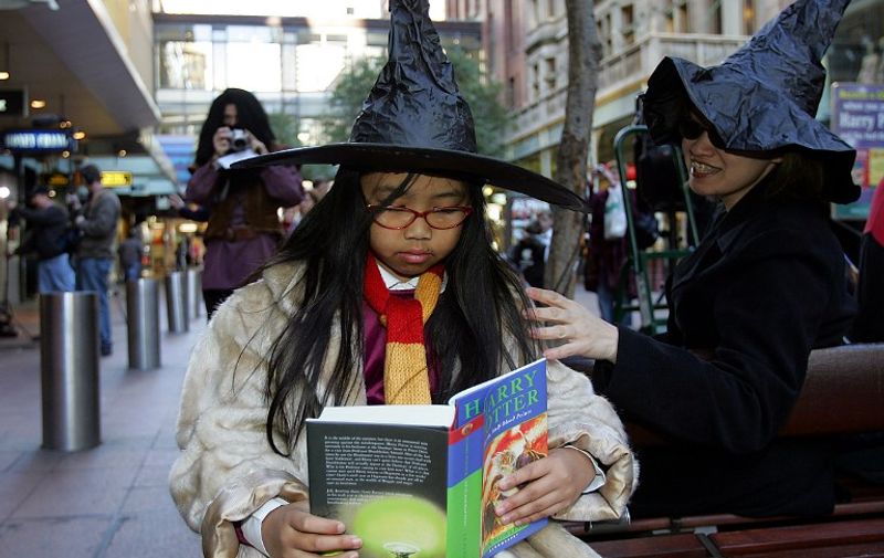 Harry Potter fan Bea Brabante (C) couldn't wait until she got home before reading the sixth book in the J.K.Rowling phenomenon -- Harry Potter and the Half-Blood Prince -- in Sydney, 16 July 2005. Approximately 270 million copies of the Harry Potter books have been sold worldwide: over 6.5 million copies in Australia alone!  AFP PHOTO/Torsten BLACKWOOD / AFP / TORSTEN BLACKWOOD