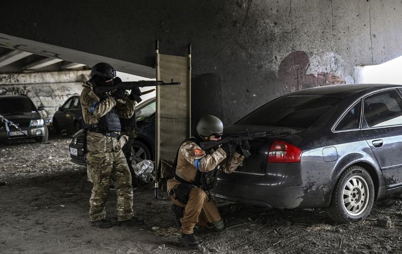 Ukrainian servicemen aim with their weapons at a moving car from a postition under a destroyed bridge in the city of Irpin, northwest of Kyiv, on March 13, 2022. - Russian forces advance ever closer to the capital from the north, west and northeast. Russian strikes also destroy an airport in the town of Vasylkiv, south of Kyiv. A US journalist was shot dead and another wounded in Irpin, a frontline northwest suburb of Kyiv, medics and witnesses told AFP. (Photo by Aris Messinis / AFP)