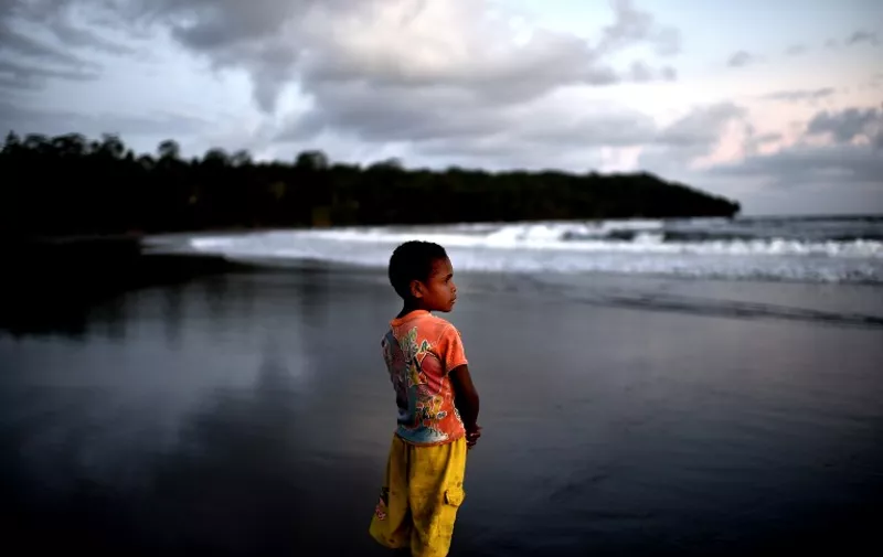 A young boy stands at sunset on the beach of Kerema, Papua New Guinea, on September 10, 2014. AFP PHOTO / ARIS MESSINIS
