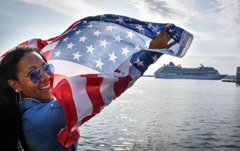 A Cuban waves a US flag at the Malecon waterfront as the first US-to-Cuba cruise ship to arrive in the island nation in decades glides into the port of Havana, on May 2, 2016. 
The first US cruise ship bound for Cuba in half a century, the Adonia -- a vessel from the Carnival cruise's Fathom line -- set sail from Florida on Sunday, marking a new milestone in the rapprochement between Washington and Havana. The ship -- with 700 passengers aboard -- departed from Miami, the heart of the Cuban diaspora in the United States. / AFP PHOTO / ADALBERTO ROQUE