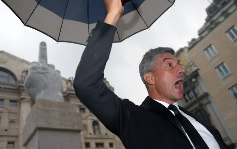 Italian artist Maurizio Cattelan poses near his sculpture depicting the middle-finger gesture during its unveiling in front of Milan stock exchange on September 24, 2010. AFP PHOTO / GIUSEPPE CACACE / AFP PHOTO / GIUSEPPE CACACE