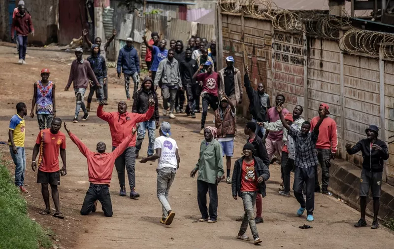 Opposition supporters react in front of Kenyan police officers during riots in the informal settlement of Kibera in Nairobi on May 2, 2023. - Kenyan riot police were out on the streets on May 2, 2023 as the opposition defied a police ban and staged new demonstrations over the cost of living crisis and last year's election results. (Photo by Luis Tato / AFP)