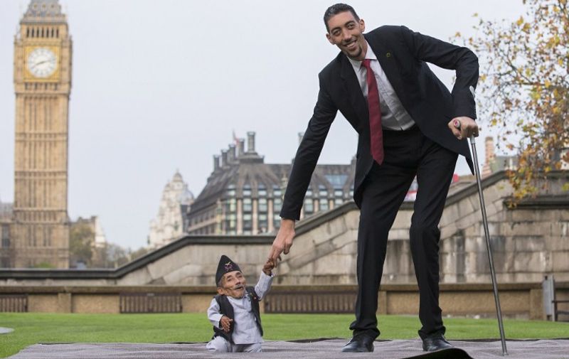Chandra Bahadur Dangi, from Nepal, (L) the shortest adult to have ever been verified by Guinness World Records, poses for pictures with the world's tallest man Sultan Kosen from Turkey, during a photocall in London on November 13, 2014, to mark Guinness World Records Day. Chandra Dangi, measures a tiny 21.5in (0.54m)  the same height as six stacked cans of beans. Sultan Kosen measures 8 ft 3in (2.51m).  AFP PHOTO / ANDREW COWIE
