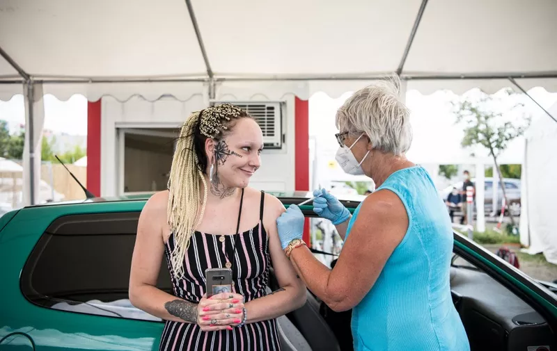 A woman is vaccinated against the COVID-19 coronavirus next to a car at a drive thru vaccination center outside an IKEA store in Berlin, on July 29, 2021, amid the novel coronavirus / COVID-19 pandemic. (Photo by STEFANIE LOOS / AFP)