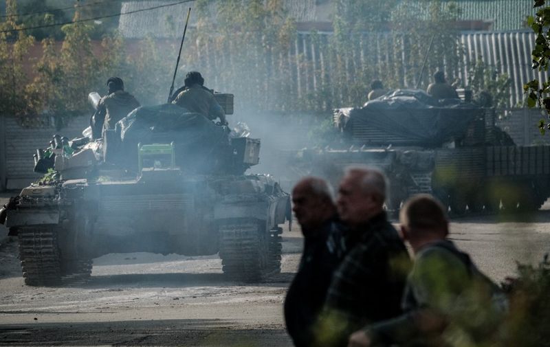 Pedestrians watch Ukrainian tanks at the recently retaken eastern side of the Oskil River in Kupiansk, Kharkiv region, on September 29, 2022, amid the Russian invasion of Ukraine. (Photo by Yasuyoshi CHIBA / AFP)