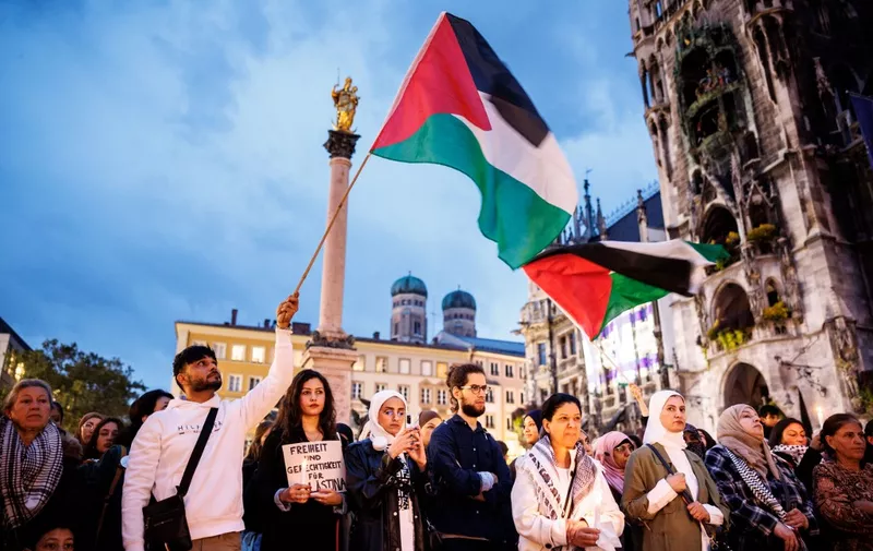 09 October 2023, Bavaria, Munich: A man waves a Palestinian flag during a rally for Palestine at Marienplatz, while a woman in front of him holds a sign reading "Freedom and Justice for Palestine." Photo: Matthias Balk/dpa (Photo by MATTHIAS BALK / DPA / dpa Picture-Alliance via AFP)