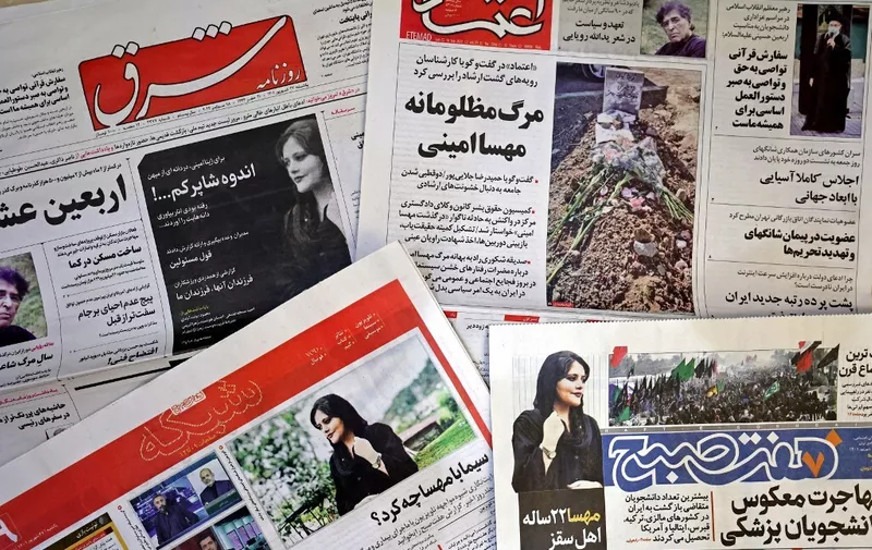 A picture taken in Tehran on September 18, 2022 shows the front pages of Iranian newspapers featuring articles and photographs of Mahsa Amini, a woman who died after being arrested by the Islamic republic's "morality police" two days ago. - Amini, 22, was on a visit with her family to the Iranian capital when she was detained on September 13 by the police unit responsible for enforcing Iran's strict dress code for women, including the wearing of the headscarf in public. She was declared dead on September 16 by state television after having spent three days in a coma. (Photo by ATTA KENARE / AFP)