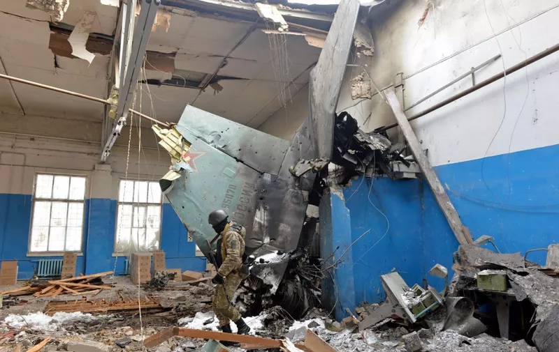 A member of the Ukrainian Territorial Defence Forces walks near remains of the Russian Sukhoi Su-25 assault aircraft crashed into the State Scientific Production Enterprise «Kommunar Corporation» in Ukraine's second-biggest city of Kharkiv on March 8, 2022. - On the 13th day of the war, the UN said the number of refugees flooding across Ukraine's borders had passed two million. (Photo by Sergey BOBOK / AFP)
