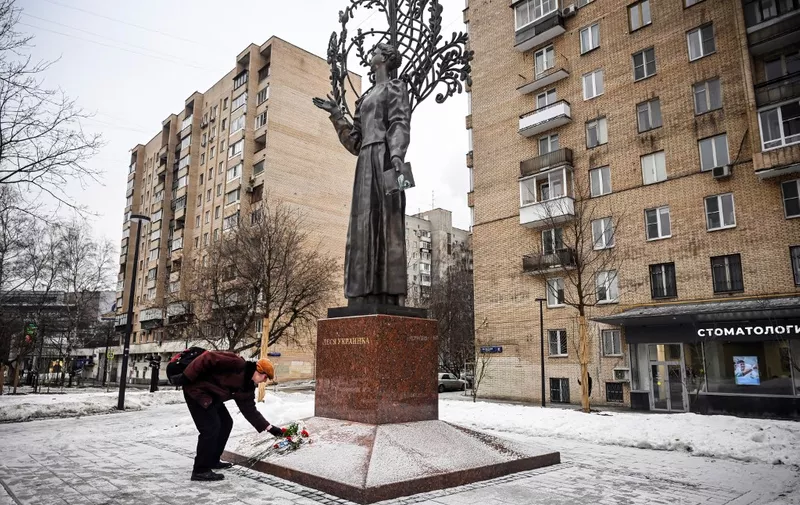 A man lays flowers in memory of those killed in a recent strike on a residential block in the Ukrainian city of Dnipro, at the monument to famous Ukrainian poetess Lesya Ukrainka in Moscow on January 23, 2023. (Photo by Alexander NEMENOV / AFP)