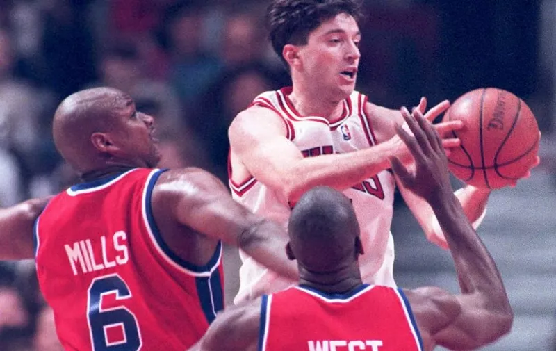 Chicago Bulls forward Toni Kukoc (C) spins around Detroit Pistons center Terry Mills (#6) and Mark West (R) in the first half 17 February at the United Center in Chicago. Kukoc scored a personal high 33 points in the Bulls' 117-102 win. (COLOR KEY: Pistons' jerseys are red.) AFP PHOTO / AFP / BRIAN BAHR