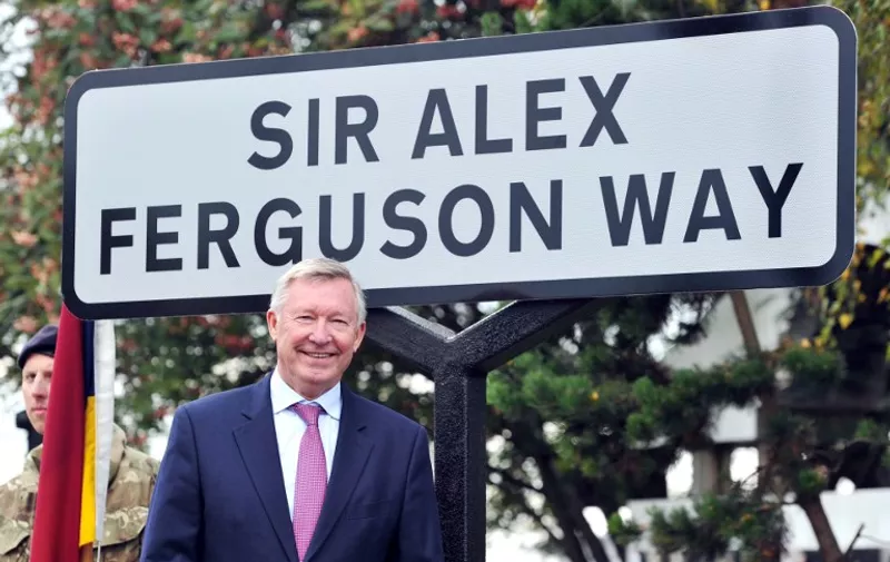 Former Manchester United manager Sir Alex Ferguson unveils a sign after a road near to Old Trafford Stadium was renamed in his honour in Manchester, north-west England, on October 14, 2013. AFP PHOTO / PAUL ELLIS