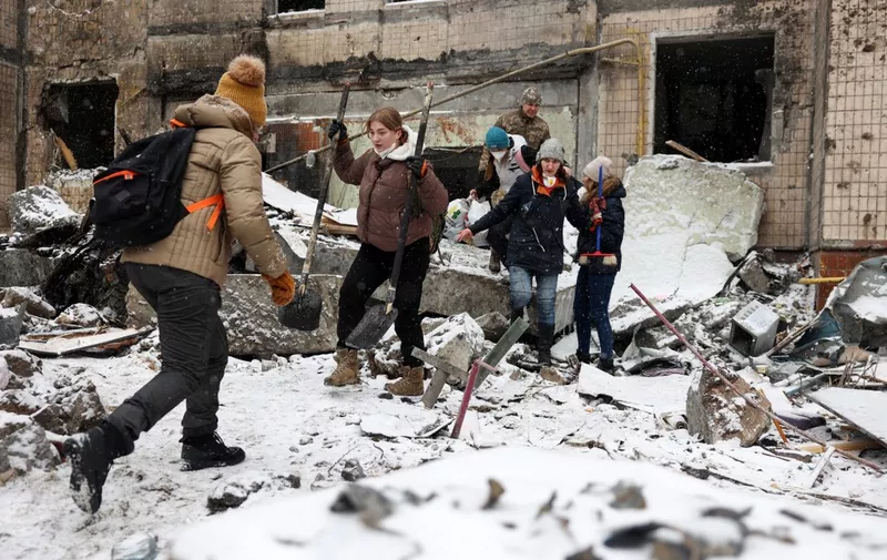 Volunteers work to clear rubble outside a high-rise building destroyed following a Russian missile attack in central Kyiv, on January 3, 2024, amid the Russian invasion of Ukraine. (Photo by Anatolii STEPANOV / AFP)