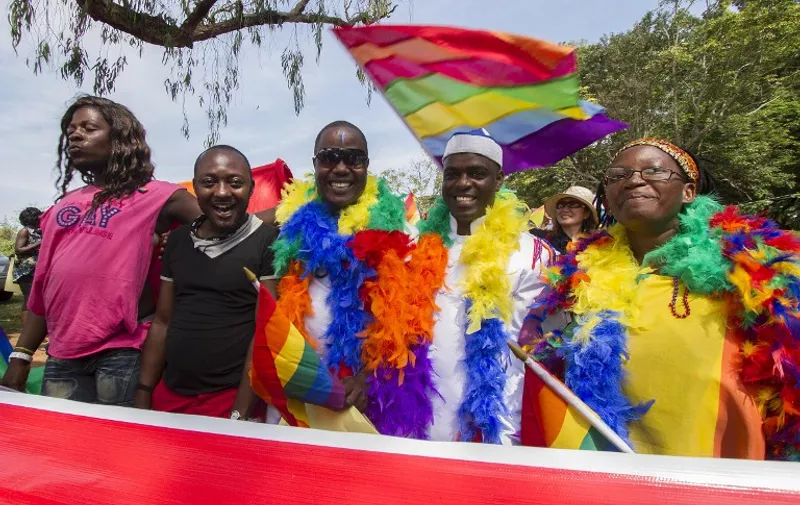 People hold rainbow flags as they take part in the Gay Pride parade in Entebbe on August 8, 2015. Ugandan activists gathered for a gay pride rally, celebrating one year since the overturning of a strict anti-homosexuality law but fearing more tough legislation may be on its way. Homosexuality remains illegal in Uganda, punishable by a jail sentence. AFP PHOTO/ ISAAC KASAMANI