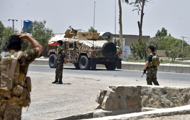 Afghan security personnel stand guard along the road amid ongoing fight between Afghan security forces and Taliban fighters in Kandahar on July 9, 2021. (Photo by JAVED TANVEER / AFP)