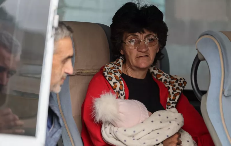 A refugee holding a baby waits in a bus before leaving the Red Cross registration center, in Goris, on September 25, 2023. The first group of Nagorno-Karabakh refugees since Azerbaijan's lighting assault against the separatist region entered Armenia on September 24, 2023, an AFP team at the border said. The group of a few dozen people passed by Azerbaijani border guards before entering the Armenian village of Kornidzor, where they were registered by officials from Armenia's foreign ministry. (Photo by ALAIN JOCARD / AFP)