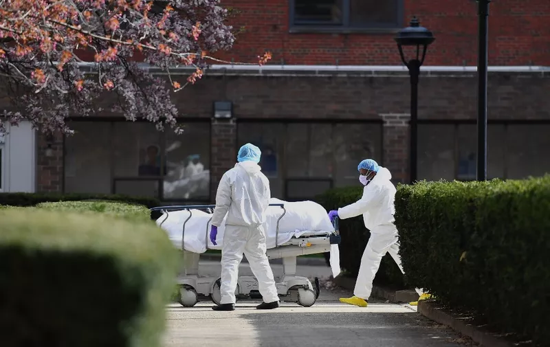 Medical personnel wearing personal protective equipment transport the body of a deceased patient from a refrigerated truck to Kingsbrook Jewish Medical Center on April 8, 2020 in Brooklyn, New York. - New York state has recorded its highest number of COVID-19 deaths in 24 hours, Governor Andrew Cuomo said on April 7, adding though that hospitalizations appeared to be "plateauing." (Photo by Angela Weiss / AFP)
