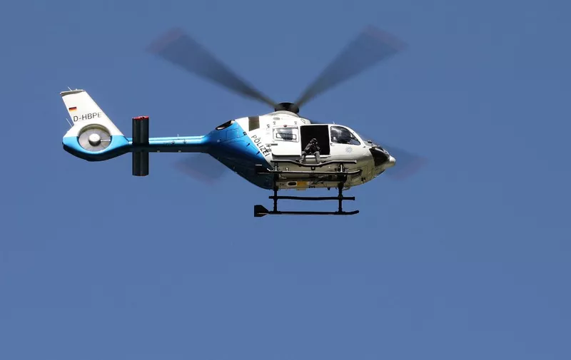 A police helicopter is seen in the air above the accident site of a derailed train near Burgrain, north of Garmisch-Partenkirchen, southern Germany, on June 4, 2022, a day after the accident. A train derailed near a Bavarian Alpine resort in southern Germany on June 3, killing at least four people and injuring dozens in a region gearing up to host the G7 summit in late June. (Photo by Dominik BARTL / AFP)