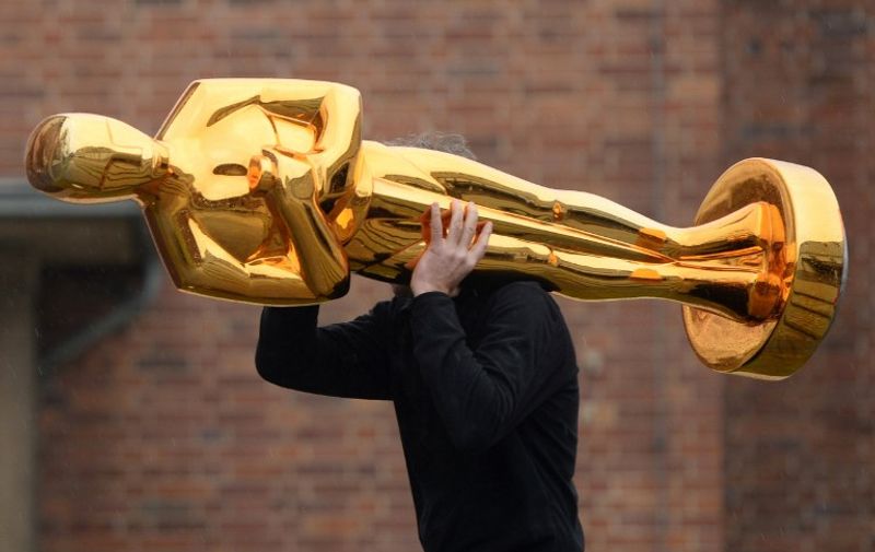 A worker carries an Oscar statue to a press event held by Filmstudios Babelsberg in Potsdam, eastern Germany following the sucess of the "Grand Budapest Hotel" at the Oscars on February 23, 2015. The film, which was awarded 4 Oscars, Best original soundtrack, Best costume design, Best make-up / hairstyling and Best production design, was co-produced by Filmstudios Babelsberg. AFP PHOTO / DPA / RALF HIRSCHBERGER   +++ GERMANY OUT +++ / AFP / DPA / RALF HIRSCHBERGER