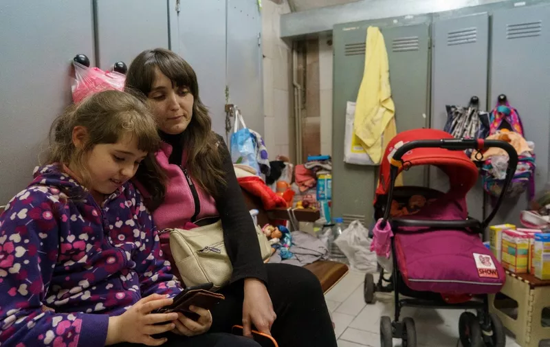 A woman, a young girl and a baby shelter from attacks in a metro station of Kharkiv on March 10, 2022. - Moscow said on March 10, 2022, that it will open daily humanitarian corridors to evacuate civilians fleeing fighting in Ukraine to Russian territory, despite Kyiv insisting that no evacuation routes should lead to Russia. (Photo by emre caylak / AFP)
