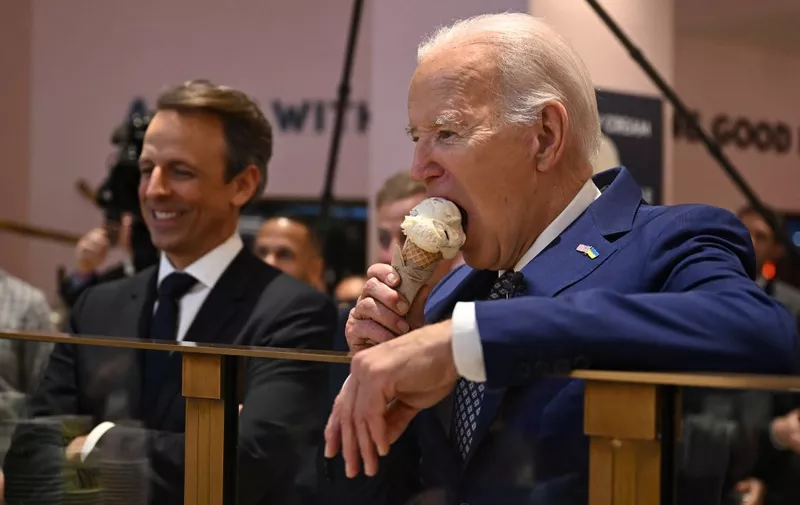 US President Joe Biden (R), flanked by host Seth Meyers (L), eats an ice cream cone at Van Leeuwen Ice Cream after taping an episode of "Late Night with Seth Meyers" in New York City on February 26, 2024. (Photo by Jim WATSON / AFP)
