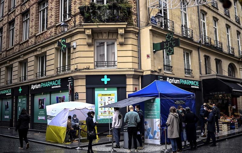 People queue for an antigenic rapid test for Covid-19 outside a pharmacy in a commercial area of central Paris on December 23, 2020, the day before Chritsmas' eve. (Photo by Christophe ARCHAMBAULT / AFP)