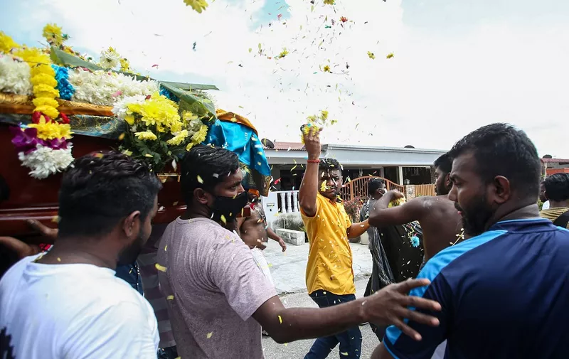 A family member throws flowers as others carry the coffin of the late Malaysian national Nagaenthran K. Dharmalingam, who was executed for trafficking heroin into Singapore, during a funeral ceremony in Tanjung Rambutan in Malaysia's Perak district, on April 29, 2022. Hundreds of mourners wept, read prayers and banged drums April 29 at the funeral of a mentally disabled Malaysian man whose hanging in Singapore this week sparked an international outcry. (Photo by Yosoff Ahmad / AFP)