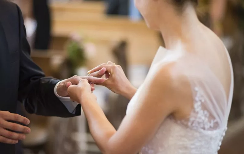 Bride placing wedding ring on bridegrooms finger in church