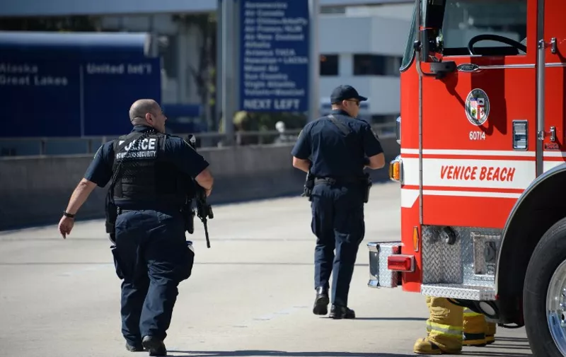 Firetrucks and police are positioned outside Terminal 3 at Los Angeles International Airport on November 1, 2013 after a gunman reportedly opened fire at a security checkpoint. A gunman opened fire with an assault rifle at Los Angeles' international (LAX) airport Friday, killing a security agent and wounding seven people, officials said. Panicked travelers scrambled to escape after the lone suspect, described by witnesses as a young white male, pulled out the gun and began shooting, walking through a security checkpoint before being stopped in an exchange of fire with police. The shooter "came into Terminal Three, pulled an assault rifle out of a bag and began to open fire ... he proceeded up into the screening area .. and continued shooting," said LAX police chief Patrick Gannon.     AFP PHOTO / ROBYN BECK / AFP / ROBYN BECK