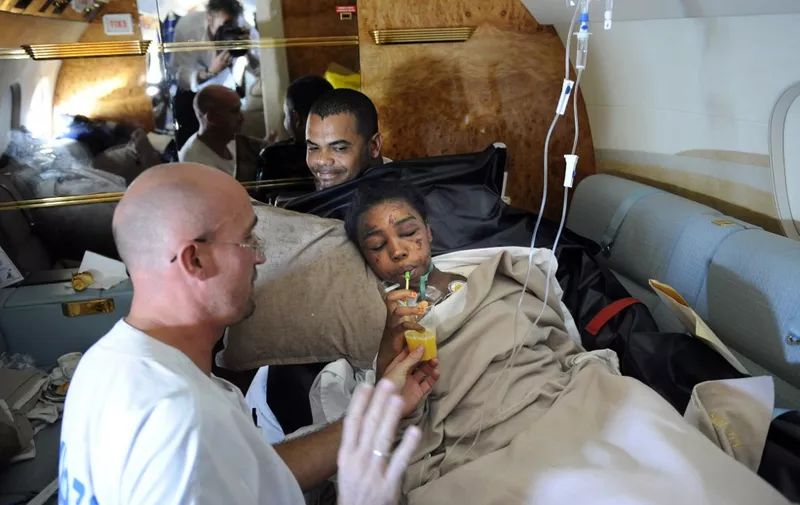 Bahia Bakari, 12, drinks juice on a plane next to medical personel, prior to her arrival at the Bourget airport, outside Paris, on July 2, 2009 after she miraculously survived the Yemenia airliner crash off the Comoros islands, being ejected from the plane into pitch-black Indian Ocean waters. The 12-year-old girl was rescued alive in the sea amid debris and dead bodies after a Yemeni Airbus jet crashed on June 30 in the Indian Ocean as it tried to land in the Comoros with 153 people aboard. The A310 had aborted a landing and was making a second attempt when it crashed. AFP PHOTO STEPHANE DE SAKUTIN (Photo by STEPHANE DE SAKUTIN / AFP)