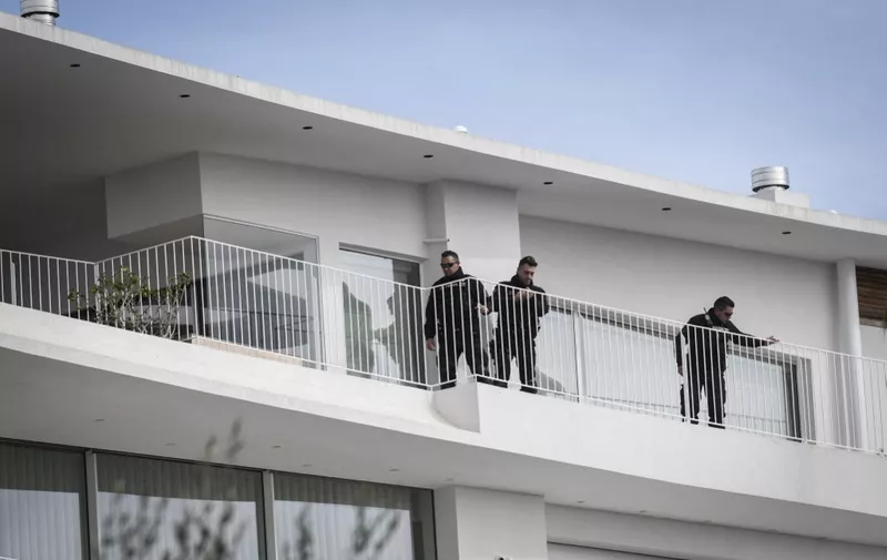 Police officers stand on the balcony of a shipping company, south of Athens, on February 12, 2024. Three people were killed on February 12, 2024, by shots fired by a man who barricaded himself in the premises of a shipping company in the seaside suburb of Athens. (Photo by Angelos Tzortzinis / AFP)