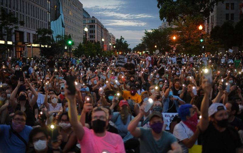 Protesters hold up their phones during a demonstration over the death of George Floyd, outside the White House on June 3, 2020 in Washington, DC. - Former Minneapolis police officer Derek Chauvin, who kneeled on the neck of George Floyd who later died, will now be charged with second-degree murder, and his three colleagues will face charges of aiding and abetting second-degree murder, court documents revealed on June 3. (Photo by Eric BARADAT / AFP)