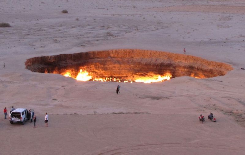 TO GO WITH AFP STORY
A picture taken on May 3, 2014, shows people visiting "The Gateway to Hell," a huge burning gas crater in the heart of Turkmenistan's Karakum desert. The fiery pit was the result of a simple miscalculation by Soviet scientists in 1971 after their boring equipment suddenly drilled through into an underground cavern and a deep sinkhole formed. Fearing that the crater would emit poisonous gases, the scientists took the decision to set it alight, thinking that the gas would burn out quickly and this would cause the flames to go out. But the flames have not gone out in more than 40 years, in a potent symbol of the vast gas reserves of Turkmenistan, which are believed to be the fourth largest in the world.  AFP PHOTO / IGOR SASIN (Photo by IGOR SASIN / AFP)