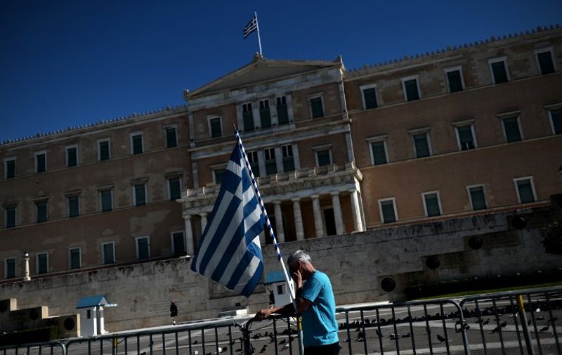 A man with a Greek flag stands in front of the Greek parliament in central Athens during protests against new austerity measures and a rally marking a 48-hours general strike, on November 6, 2012. Tens of thousands of Greeks poured into the streets on Tuesday as mass strikes paralysed Athens in the latest show of anger over a new government austerity bill aimed at securing international aid needed to prevent the debt-crippled nation from defaulting. AFP PHOTO / ARIS MESSINIS