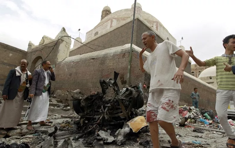 Yemenis react next to the wreckage of a vehicle outside the Kobbat al-Mehdi Shiite mosque in the capital Sanaa on June 20, 2015, after a car bomb targeting the area killed two people. The explosion in Sanaa, controlled by Iran-backed Shiite Huthi rebels, went off outside the mosque as Shiite Muslims emerged from midday prayers, witnesses and security sources said. AFP PHOTO / MOHAMMED HUWAIS