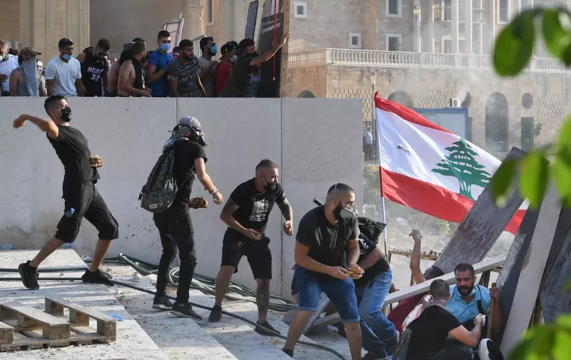 Lebanese protesters duck for cover during clashes with security forces in downtown Beirut on August 8, 2020, following a demonstration against a political leadership they blame for a monster explosion that killed more than 150 people and disfigured the capital Beirut. (Photo by - / AFP)