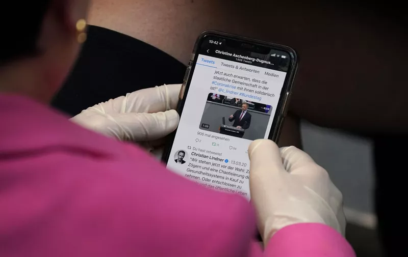 BERLIN, GERMANY - MARCH 25: A member of the Bundestag wears protective gloves as she follows a Twitter feed on a smartphone during debates at the Bundestag prior to the likely passing of a massive federal financial aid package to shore Germany up against the effects of the coronavirus on March 25, 2020 in Berlin, Germany. The Bundestag is expected to pass the package worth over EUR 150 billion later today.  (Photo by Sean Gallup/Getty Images)