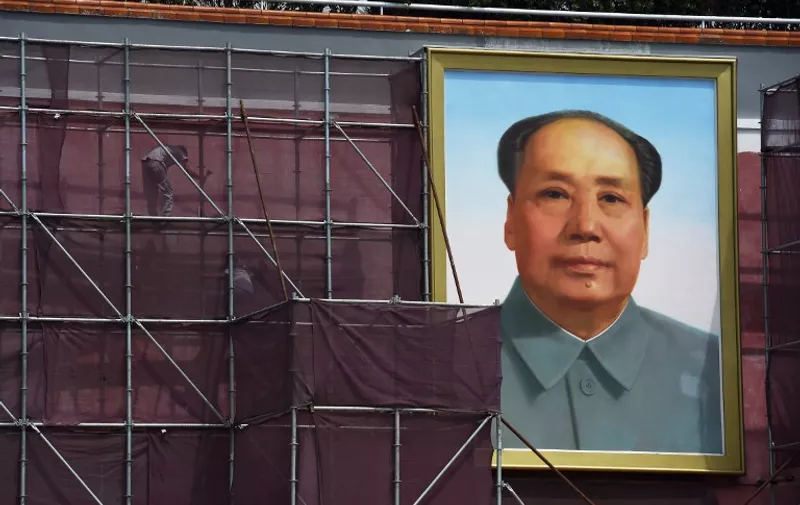 Workers stand on scaffolding while working next to the portrait of late communist leader Mao Zedong on Tiananmen rostrum in Beijing's Tiananmen Square on July 23, 2015. The rostrum is being renovated ahead of a massive military parade on September 3 to mark the 70th anniversary of the end of China's war against Japan and World War II. AFP PHOTO / GREG BAKER