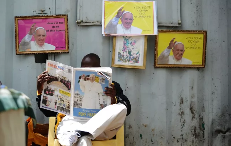 TOPSHOTS
A man reads a copy of the "Catholic Mirror" newspaper next to pictures of Pope Francis at the Holy Family Basilica in Nairobi November 22, 2015. The Saint Joseph parish of the Kenyan capital Nairobi is expected to host a mass led by Pope Francis, who arrives in Kenya in two-days on a historic visit to East and Central Africa. Pope Francis heads to Africa this week for the riskiest trip of his papacy, defying danger with an open-topped popemobile and visits to a slum, refugee camp and mosque despite security fears following jihadist attacks. AFP PHOTO / TONY KARUMBA / AFP / SIMON MAINA