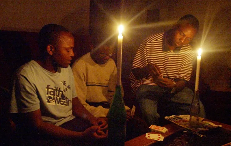A Zimbabwean family plays card 21 January 2007 in Harare after the second power cut, which has hit most parts of the country.   Zimbabwe is experiencing a serious energy crisis with some areas going for up to 10 hours without electricity prompting many families to resort to using generators, firewood and candles for lighting. AFP PHOTO/Desmond Kwande