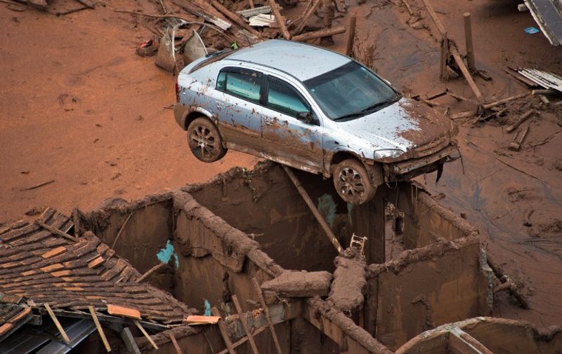 Aerial view of damages after a dam burst in the village of Bento Rodrigues, in Mariana, Minas Gerais state, Brazil on November 6, 2015. A dam burst at a mining waste site unleashing a deluge of thick, red toxic mud that smothered a village killing at least 17 people and injuring some 75. The mining company Samarco, which operates the site, is jointly owned by two mining giants, Vale of Brazil and BHP Billiton of Australia. AFP PHOTO /  CHRISTOPHE SIMON