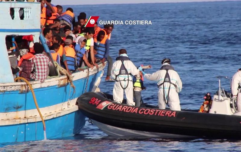 In this video grab released by the Italian Coast Guards (Guardia Costiera) on August 23, 2015 children migrants are helped by rescuers during a rescue operation off the coast of Libya as part of the Frontex-coordinated Operation Triton. Italy's coastguard coordinated the rescue of 4,400 migrants from boats in the Mediterranean in a single day on August 22, 2015, officials said. Saturday's total was thought to be the highest for a single day in recent years as calm conditions encouraged people smugglers to leave Libya with boats stuffed with as many paying passengers on board as possible. The coastguard said it had received distress calls from a total of 22 vessels, either inflatable dinghies or wooden former fishing boats -- all of them dangerously overcrowded and many of them lacking basic safety equipment. AFP PHOTO / HO
= RESTRICTED TO EDITORIAL USE - MANDATORY CREDIT "AFP PHOTO / GUARDIA COSTIERA" - NO MARKETING NO ADVERTISING CAMPAIGNS - DISTRIBUTED AS A SERVICE TO CLIENTS =