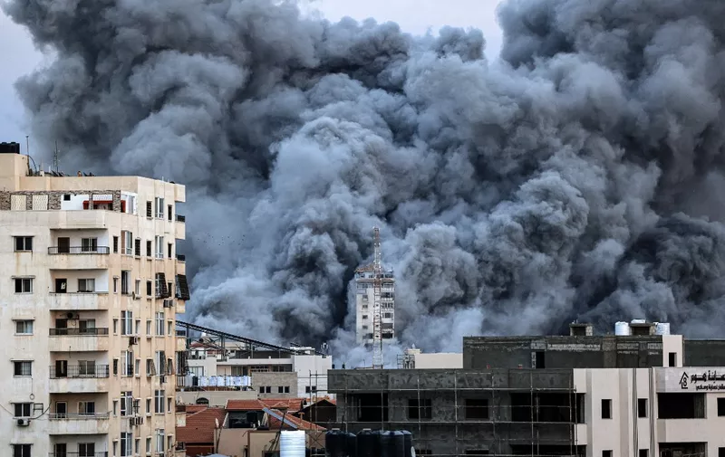 EDITORS NOTE: Graphic content / A plume of smoke rises above buildings in Gaza City on October 7, 2023 during an Israeli air strike that hit the Palestine Tower building. At least 70 people were reported killed in Israel, while Gaza authorities released a death toll of 198 in the bloodiest escalation in the wider conflict since May 2021, with hundreds more wounded on both sides. (Photo by MAHMUD HAMS / AFP)