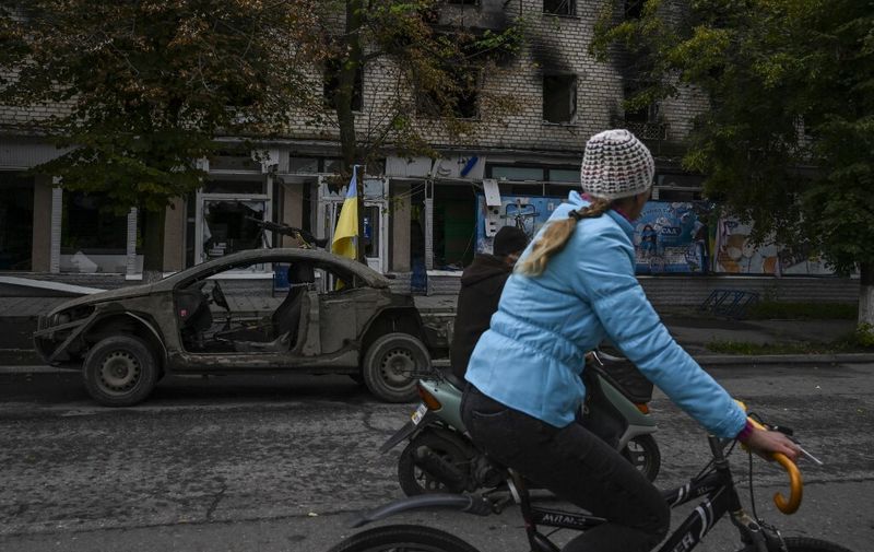 A local resident rides a bycicle on a street in Izyum, eastern Ukraine on September 14, 2022. - Ukrainian President on September 14, 2022 promised "victory" on a visit to the strategic city of Izyum that was recently recaptured from Russia by Kyiv's army in a lightning counter-offensive. (Photo by Juan BARRETO / AFP)