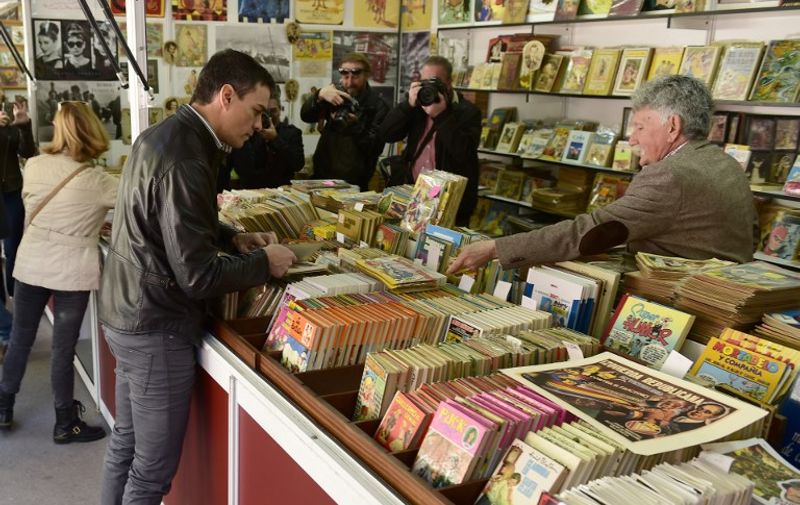 Leader of the Socialist Party (PSOE) Pedro Sanchez checks books at the Old Books Fair before to take part to the traditional May Day rally in Madrid on May 1, 2016. / AFP PHOTO / PIERRE-PHILIPPE MARCOU