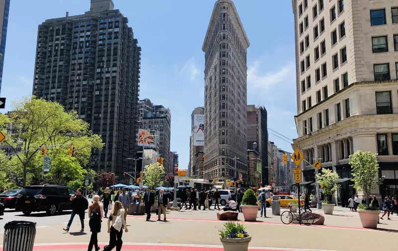 People walk past the Flatiron Building in New York City on May 7, 2019. (Photo by Daniel Slim / AFP)