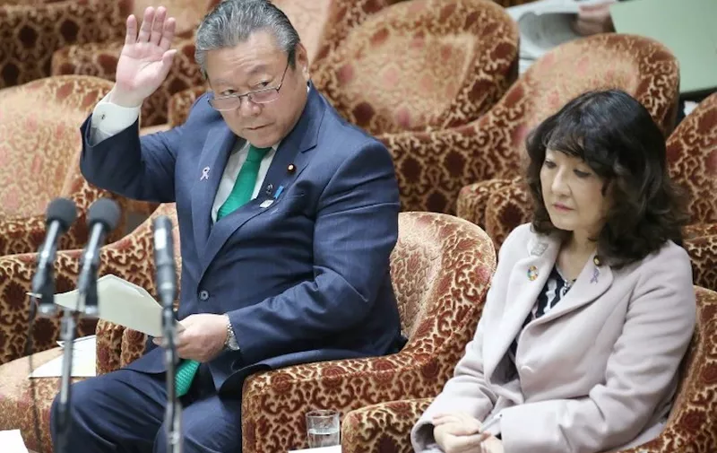 This picture taken on November 14, 2018 shows Yoshitaka Sakurada (L), 68, the deputy chief of the government's cyber security strategy office and also the minister in charge of the Olympic and Paralympic Games that Tokyo will host in 2020, raising his hand to answer a question beside Satsuki Katayama (R), minister in charge of regional revitalisation and female empowerment, during a parliament session in Tokyo. - Sakurada on November 14 provoked astonishment by admitting he has never used a computer in his professional life, and appearing confused by the concept of a USB drive. (Photo by JIJI PRESS / JIJI PRESS / AFP) / Japan OUT