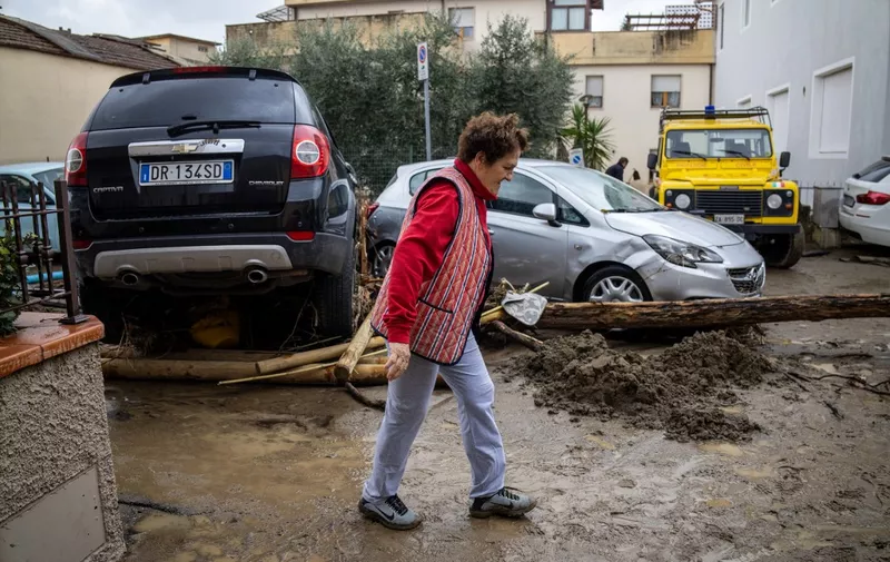 A woman walks past debris and damaged cars in Montemurlo, near Prato, after heavy rain last night, on November 3, 2023. Storm Ciaran hit Tuscany late on November 2, 2023 causing the death of five people according to authorities. (Photo by Federico SCOPPA / AFP)