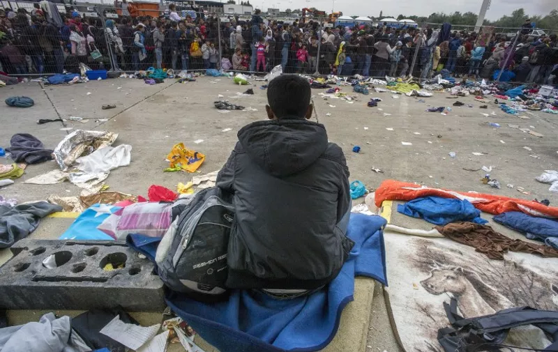 One migrant sits as hundreds are waiting for buses at the former truck custom station near Nickelsdorf, Austria at the border between Hungary and Austria on September 11, 2015. Over eight thousand migrants passed through this location the day before and the same number is expected for today. AFP PHOTO/JOE KLAMAR / AFP / JOE KLAMAR