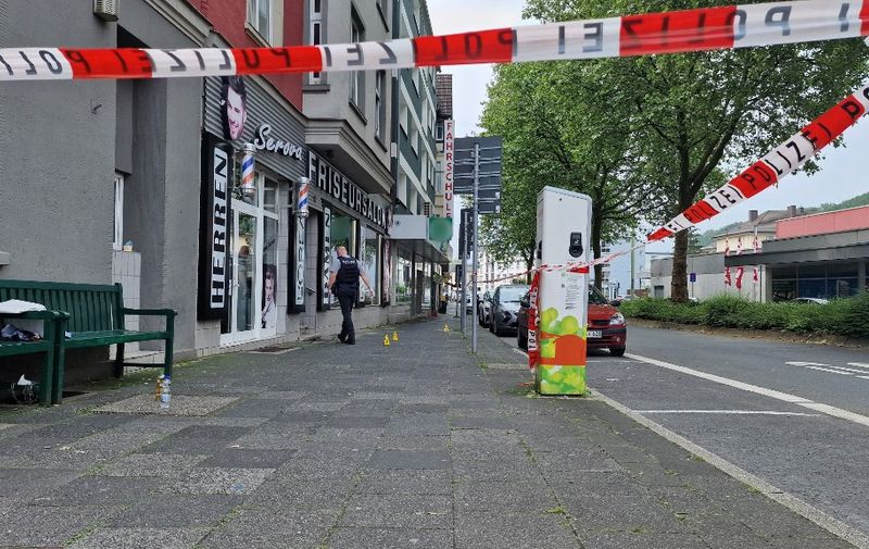 01 June 2024, North Rhine-Westphalia, Hagen: A policeman walks behind a police cordon to a hairdressing salon. A total of four people were injured by shots fired at two locations in Hagen on Saturday. One person suffered life-threatening injuries, said a spokesman for the Dortmund police, who were in charge of the incident. The police did not initially provide any further details. According to the police, one perpetrator was on the run early Saturday afternoon. They are searching for him at full speed. However, Dortmund police did not rule out the possibility that there could be several perpetrators. Photo: Justin Brosch/dpa - ATTENTION: Shop signs have been pixelated for legal reasons (Photo by Justin Brosch / DPA / dpa Picture-Alliance via AFP)